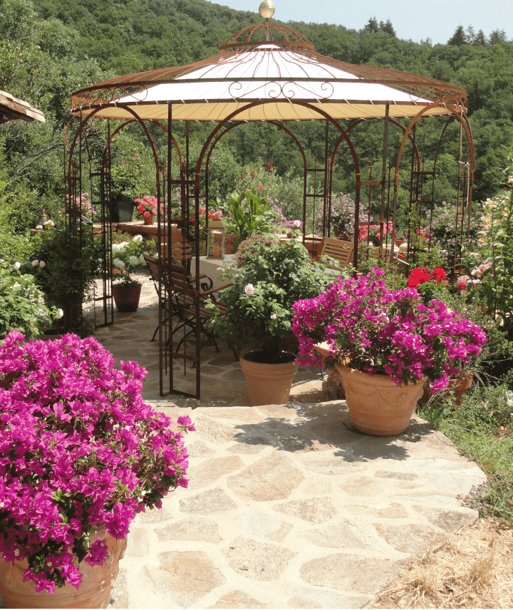 Pavillon Florenz in unbeschichteter Ausführung mit Sonnensegel und Messingkugel umgeben von blühenden Pflanzen