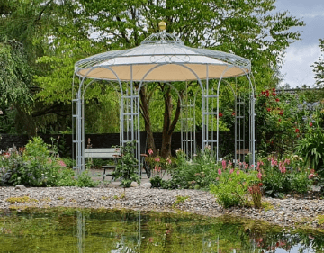 Pavillon Florenz in feuerverzinkt mit Sonnensegel neben einem Teich mit Pflanzen